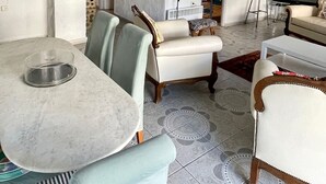 A modern living room with a dining area, featuring a white sofa, a dining table, and a television.