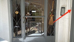 A grey door with a decorative glass panel and a metal gate.