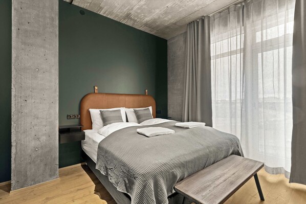 A modern bedroom with a bed, bedside tables, and a bench.