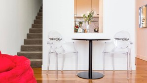 A modern living room with a staircase, a round table, and two clear chairs with a logo. - Oversized Designer Warehouse in Surry Hills / City (Surry Hills)