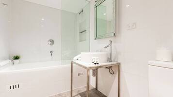 A modern bathroom with a glass shower enclosure, a freestanding sink, and a toilet.