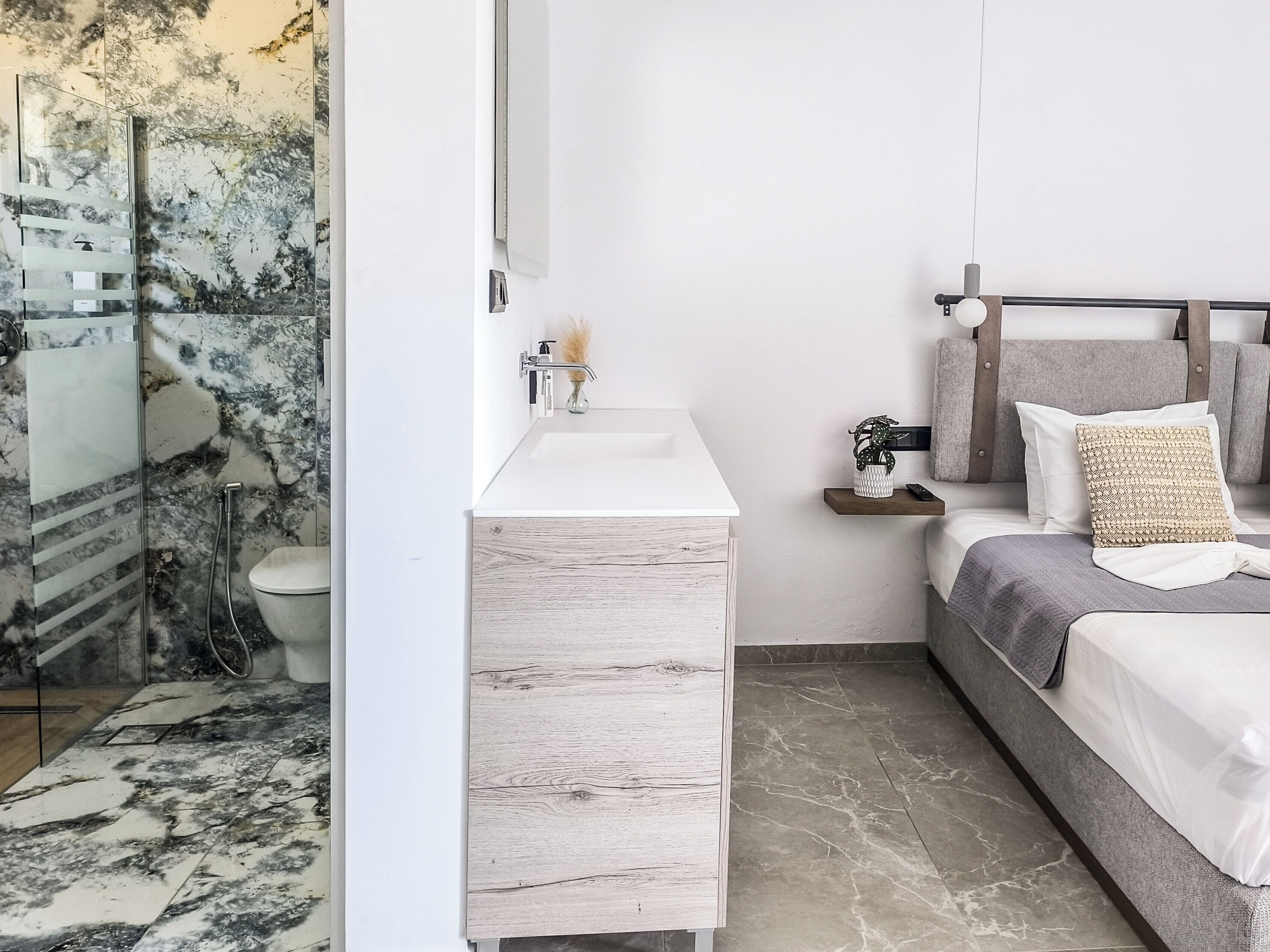 A modern bathroom with a glass shower enclosure, a white sink, and a wooden vanity.