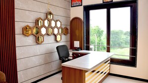 A modern office with a desk, chair, and decorative wall art. - Prabhu Chhaya Hotel (Kapasan)