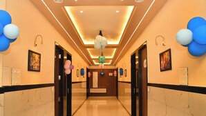 A hotel corridor with marble walls, a polished floor, and ceiling lights. - Prabhu Chhaya Hotel (Kapasan)