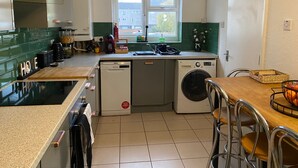Une cuisine compacte équipée d’un lave-vaisselle, d’un lave-linge et d’une fenêtre laissant entrer la lumière naturelle.