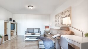 Un salon moderne avec un canapé, une table basse, un bureau et une lampe.