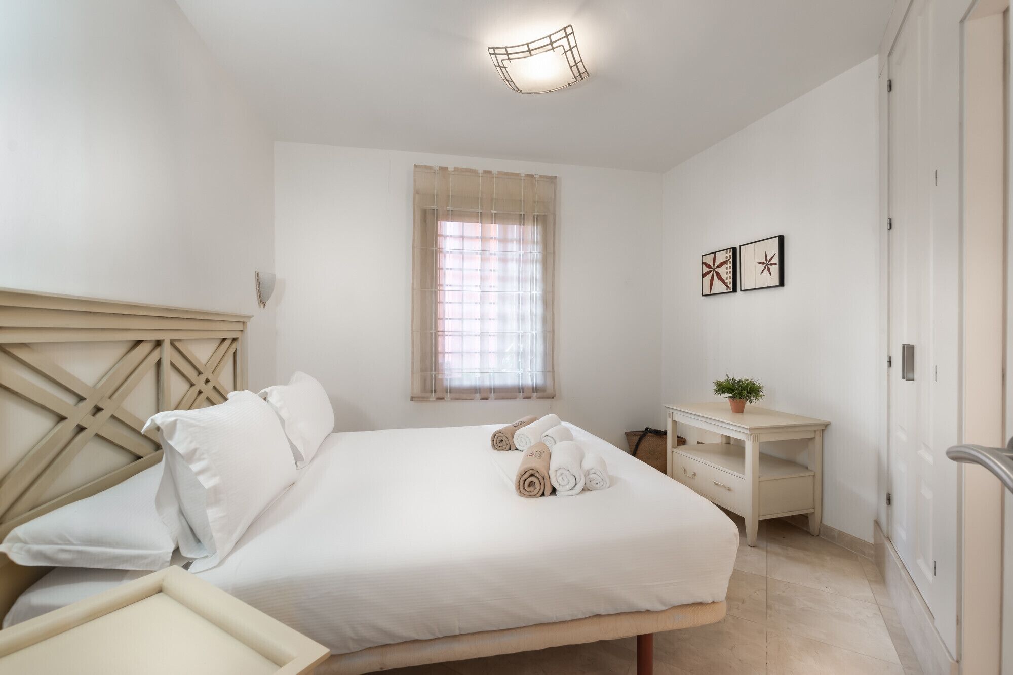A bedroom with a bed, bedside table, and a window with curtains.