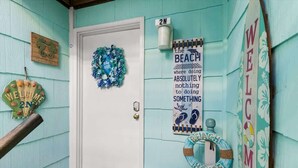 A turquoise house with a white door, a welcome sign, a beach-themed sign, and a beach house sign. - Sunset Shores at Dune Mist (Ocean City)