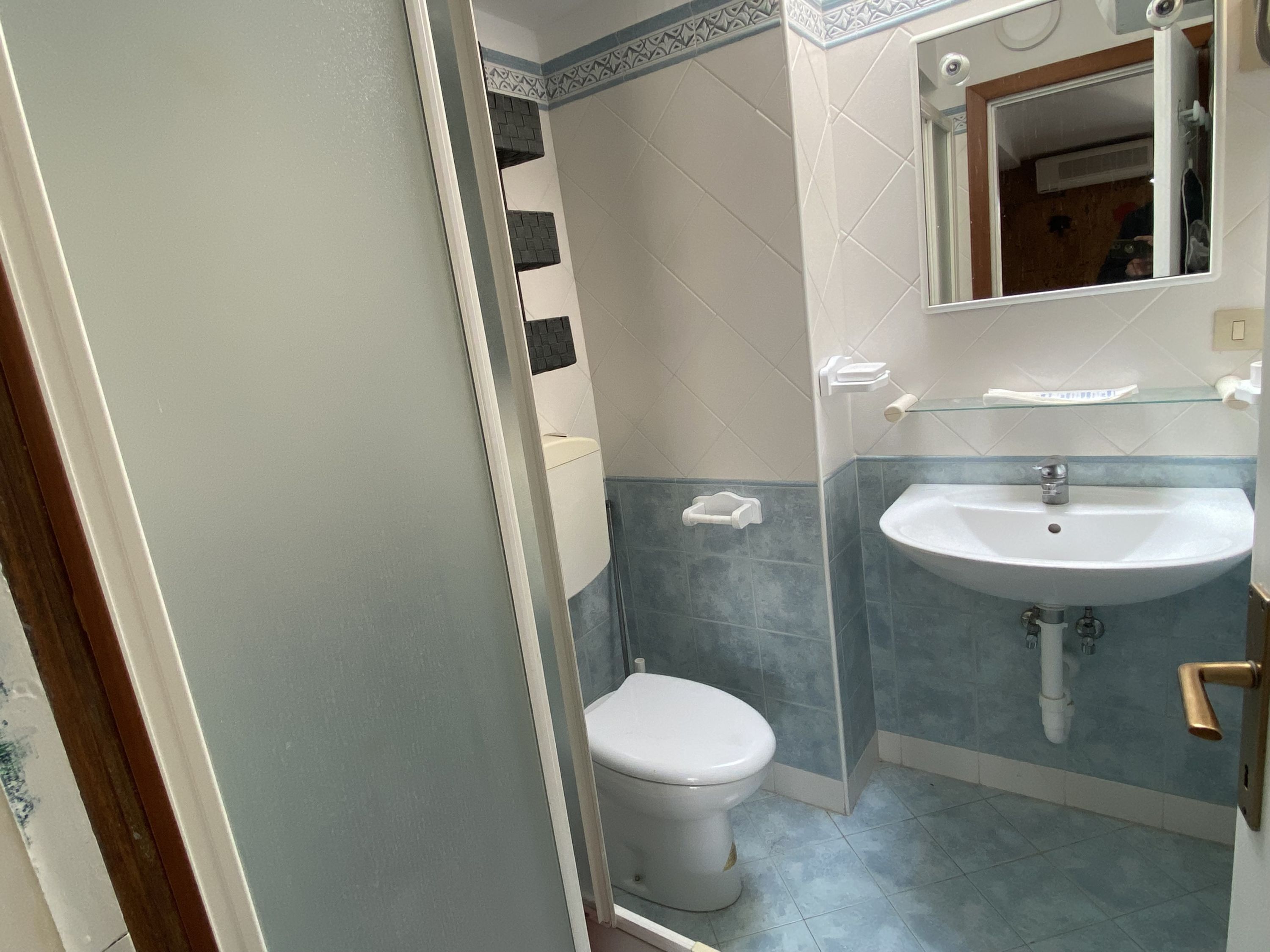 Een badkamer met toilet, wastafel en spiegel.