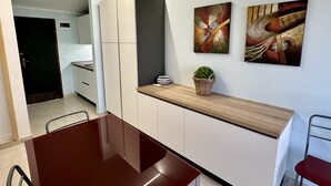 A modern kitchen with white cabinets, a wooden countertop, and two abstract paintings on the wall. - Foyer in Bibione With 1 Bedrooms and 1 Bathrooms (San Michele al Tagliamento)