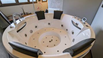 Une salle de bain moderne avec une grande baignoire ronde, un lavabo et une fenêtre laissant entrer la lumière naturelle.