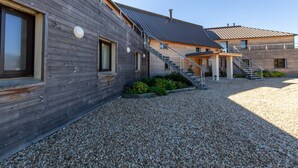 A modern building with a wooden facade, a gravel courtyard, and a metal roof. - Cottage in Sologne with leisure and activities nearby (Jouy-le-Potier)