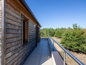 Eine Holzhütte mit einem Balkon mit Blick auf ein bewaldetes Gebiet.