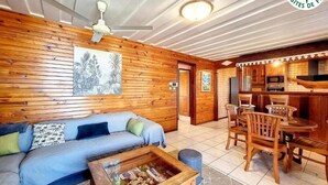 Een gezellig cabin interieur met een houten wand, een bank, een eettafel en een keukenhoek.