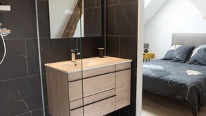 Un baño moderno con tocador, espejo y ducha.