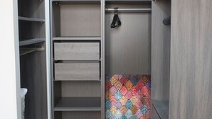 Un armario vestidor con estantes abiertos, una barra para colgar y una pared con un estampado colorido.