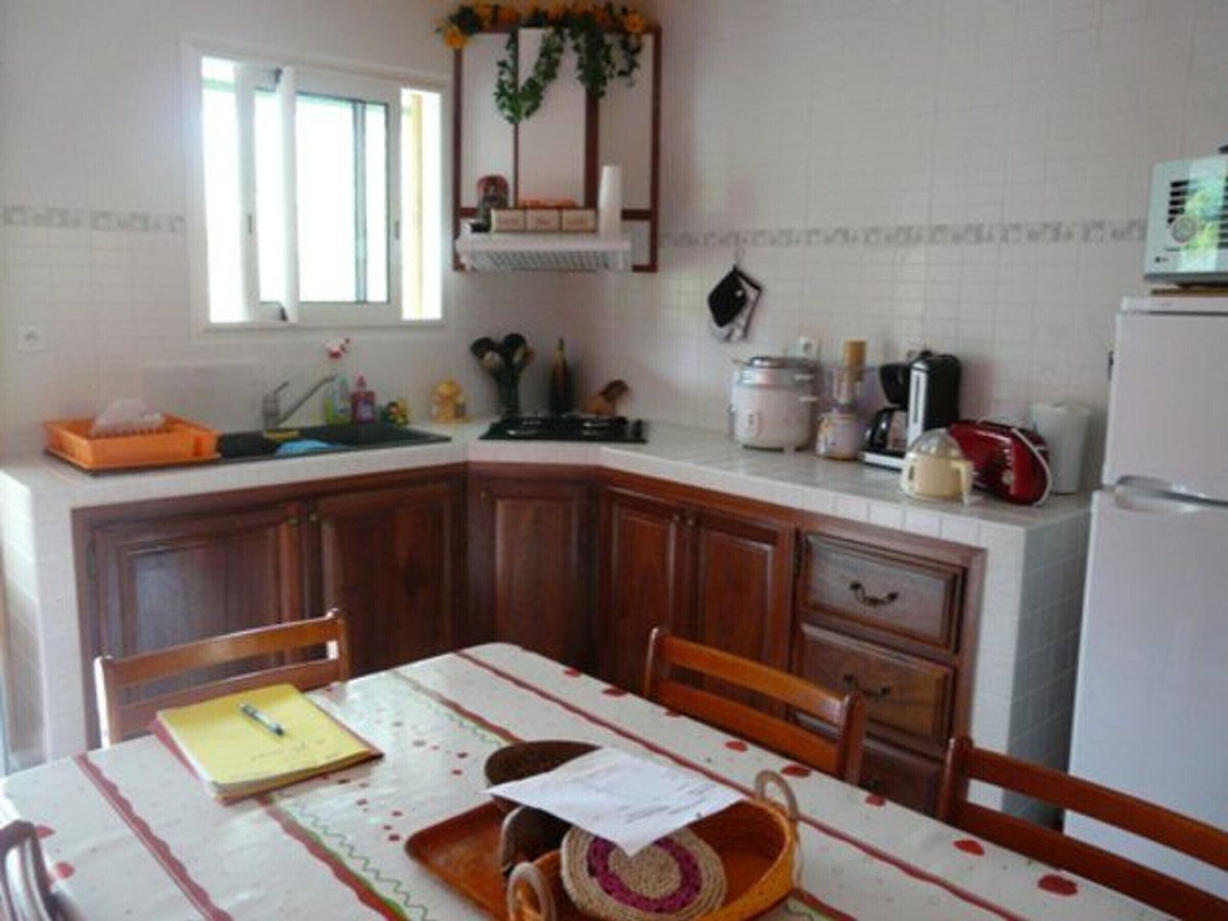 Una cucina con mobili in legno, un piano di lavoro bianco, un lavello, un fornello e un frigorifero.