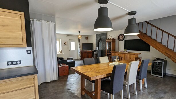 A modern kitchen with a wooden table and chairs, a built-in oven, and a dining area with a large clock and a fireplace. - Family home near castles, Loire cycling, private parking (Messas)