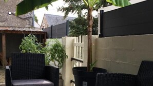 A patio area with wicker furniture, a potted plant, and a thatched-roof structure. - Family home near castles, Loire cycling, private parking (Messas)