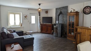Un salon moderne avec un canapé, un téléviseur, une cheminée en pierre et un meuble en bois.