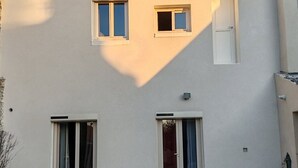Un bâtiment avec deux fenêtres au rez-de-chaussée, un petit balcon et une porte.