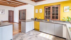 Cucina con parete gialla a contrasto, mobili in legno e pavimento in piastrelle esagonali.