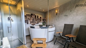 A modern bathroom with a freestanding bathtub, a vanity with a sink, and two wicker chairs.