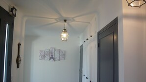 Ein Flur mit Deckenventilator, Wandleuchte und Tür mit dunklem Rahmen.