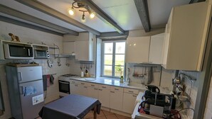 A compact kitchen with white cabinets, a gas stove, a microwave, and a refrigerator.