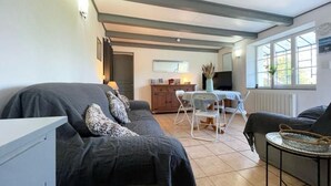 A cozy living room with a sofa, a dining table with chairs, and a TV.
