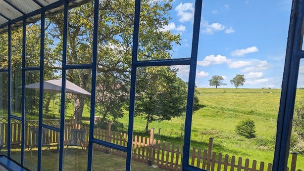 A view through a window with a wooden fence and a grassy field.
