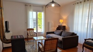 Ein Wohnzimmer mit einer Couch, Sesseln, einem kleinen Tisch, einer Lampe und einer Heizung.
