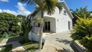 A white building with a covered porch and a palm tree in front. - Spacious stay in Saint-Louis, perfect for hiking and beach (Saint-Louis)