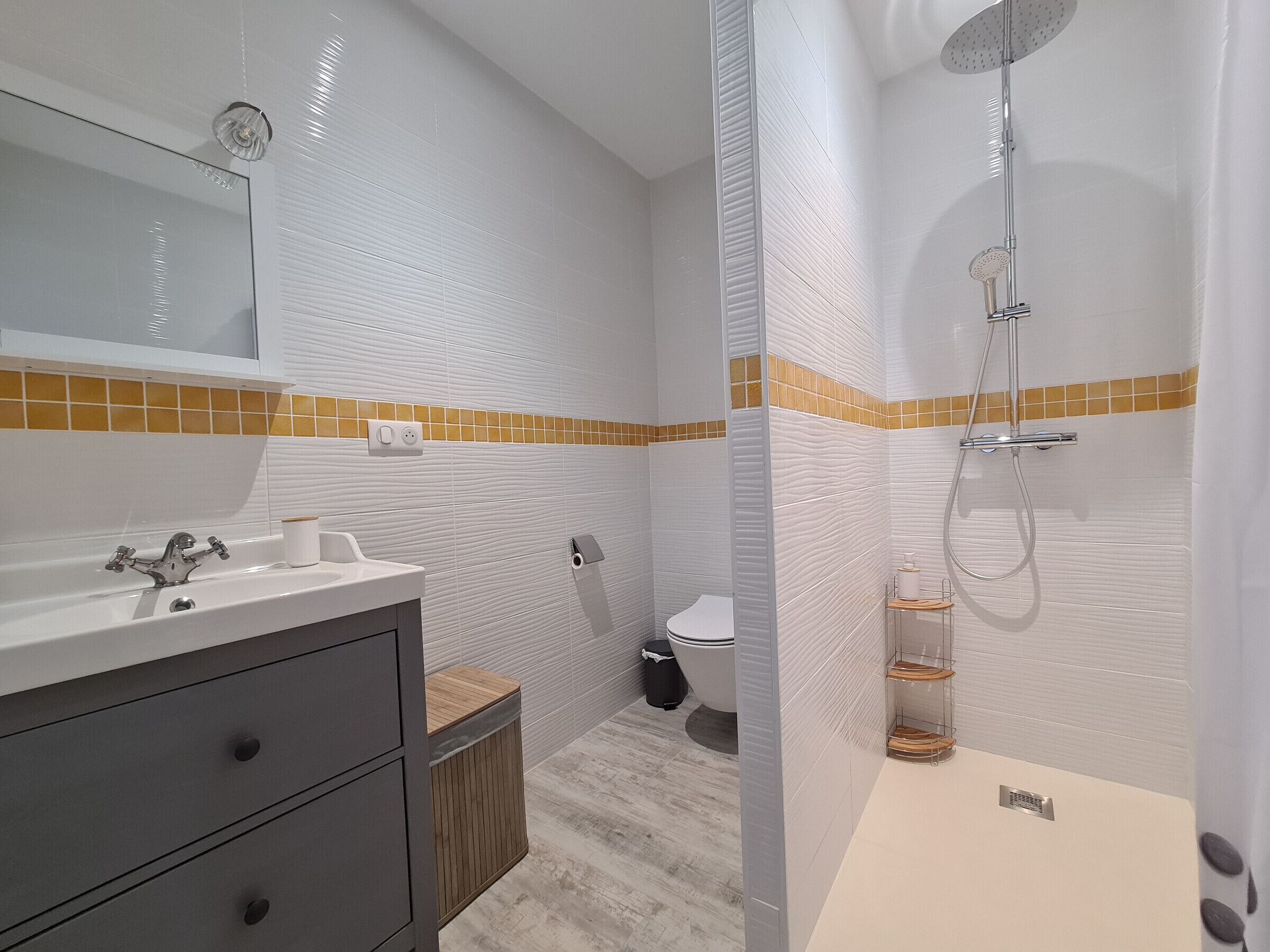 Une salle de bain moderne avec un lavabo blanc, un miroir et une douche.