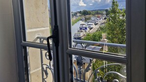 A view from a window overlooking a canal with boats and a bridge. - Large Cottage in Briare - Pets and Private Parking (Briare)