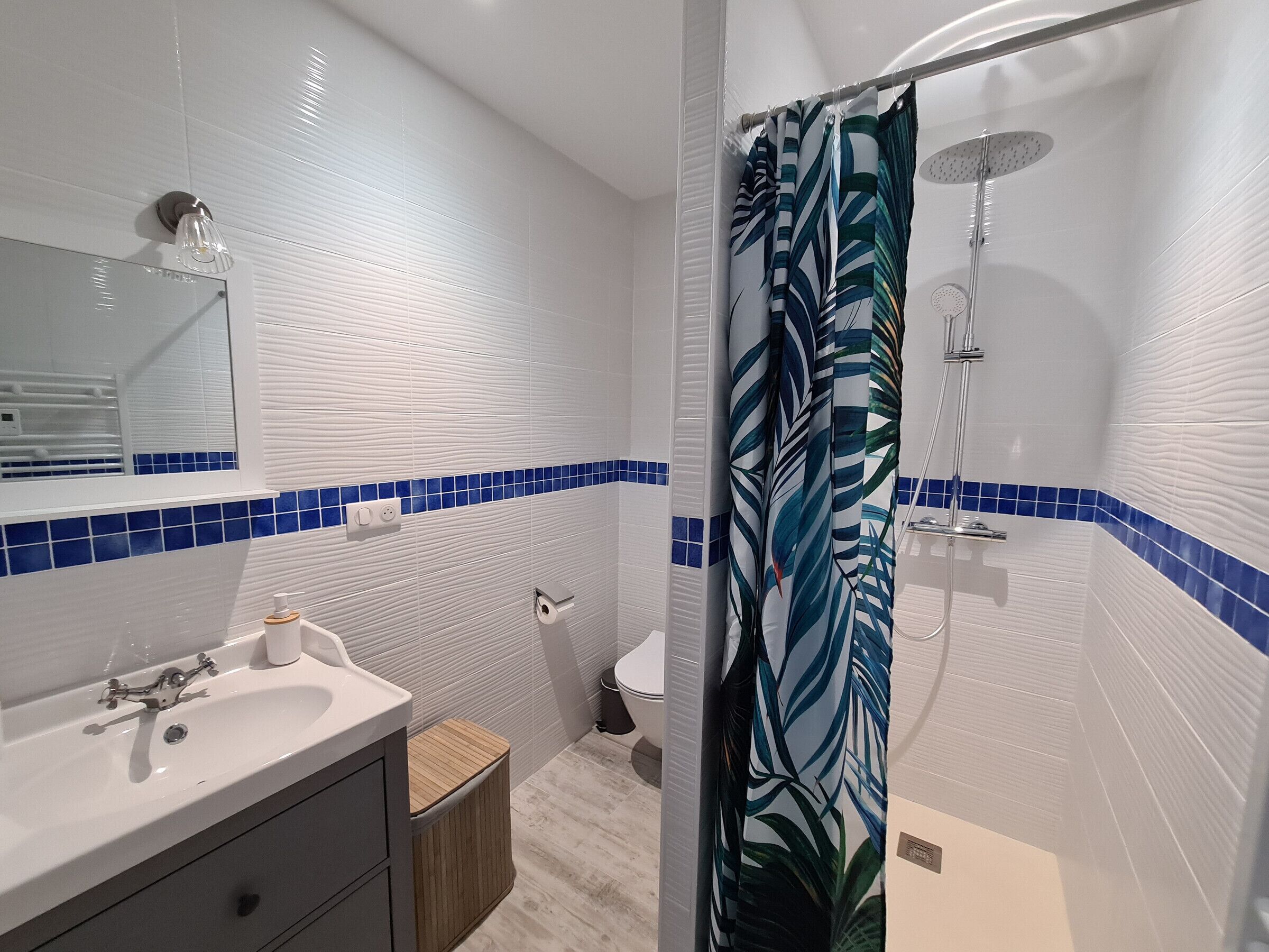 A bathroom with a white sink, mirror, and blue-tiled walls.