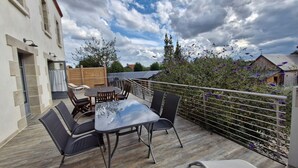 A rooftop patio with a table and chairs, a wooden deck, and a view of surrounding buildings and trees. - Large Cottage in Briare - Pets and Private Parking (Briare)