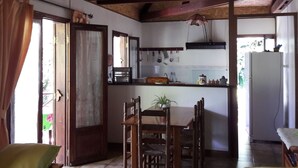 Une cuisine avec des meubles de rangement en bois, une table à manger avec des chaises et un luminaire suspendu.
