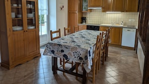 A kitchen with wooden cabinets, a dining table with chairs, and a tiled floor.