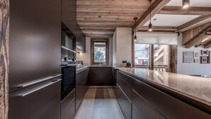 Een moderne keuken met donkere kastjes, een centraal eiland en een houten plafond.