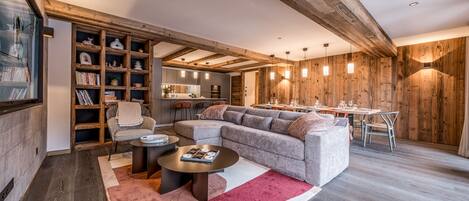 A modern living room with a sectional sofa, a coffee table, and a bookshelf.