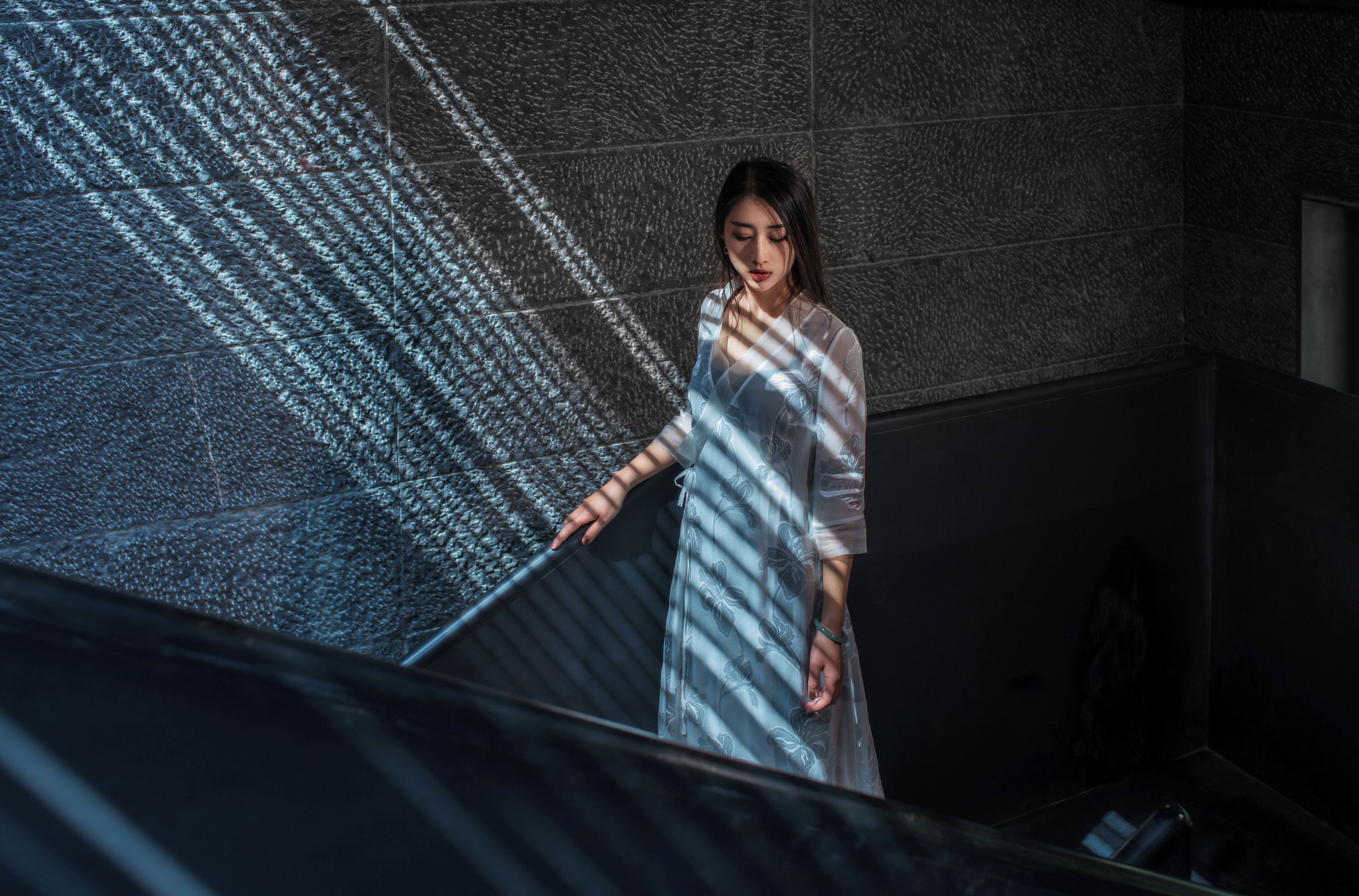 A person standing on a staircase with a patterned wall behind them.