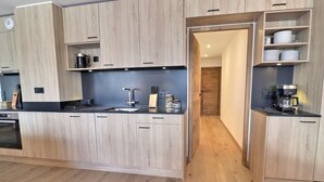 Een moderne keuken met houten kastjes, een ingebouwde oven en een koffiezetapparaat.