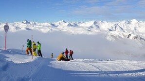 Eine verschneite Berglandschaft mit Skifahrern und blauem Himmel.