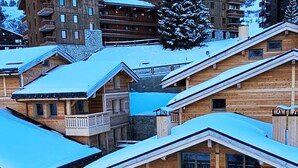 Eine Gruppe Holzhütten mit Balkonen, schneebedeckten Dächern und einer Bergkulisse.