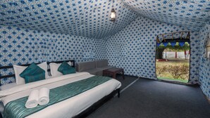 A tent-style room with a bed, a sofa, a small table, and a window with a view of greenery. - Royal River Resort Rishikesh  (Rishikesh)