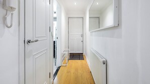 A hallway with white walls, a wooden floor, and a white radiator. - |Modern Two Bed Apt with free Gated Parking Space| (London)