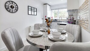 A modern dining area with a round table, white chairs, and a decorative vase. - |Modern Two Bed Apt with free Gated Parking Space| (London)