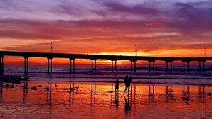 Un muelle se adentra en el agua con un atardecer de fondo.