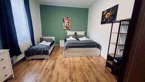 A bedroom with two beds, a white dresser, a nightstand, and a bookshelf. - Cozy Koblenz Apartment With City Views (Koblenz)